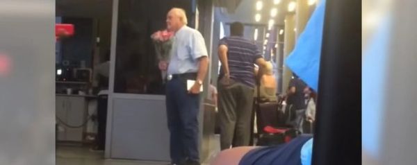 Elderly man secretly filmed waiting for his wife at airport with chocolate and flowers