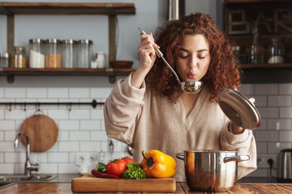 A woman tasting her own cooked food