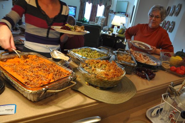 A woman serving Thanksgiving dinner while an older lady waits for her turn | Source: Flickr