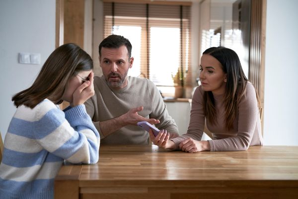 A man and woman talking to a crying girl. | Source: Shutterstock