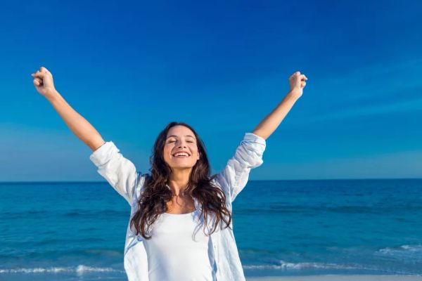 A woman smiling happily on the beach