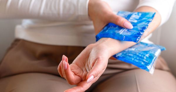 Close up of a woman applying a cold compress to her painful wrist.