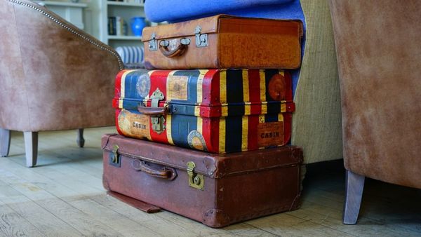 Vintage luggage stacked. Chairs and home décor in the background.