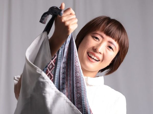 A woman holding a tote bag. White background.