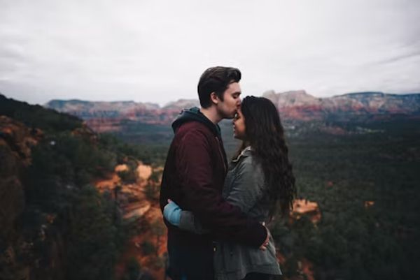 A couple kissing and holding one another on a mountain