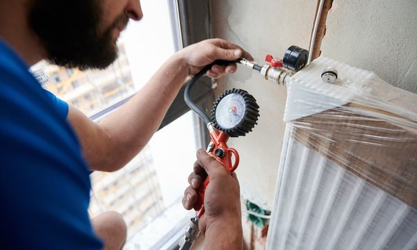 Close up of plumber filling pipes with pressurized air to inspect for leaks in new installation, using air compressor while checking gas tightness of heating system. Concept of home renovation