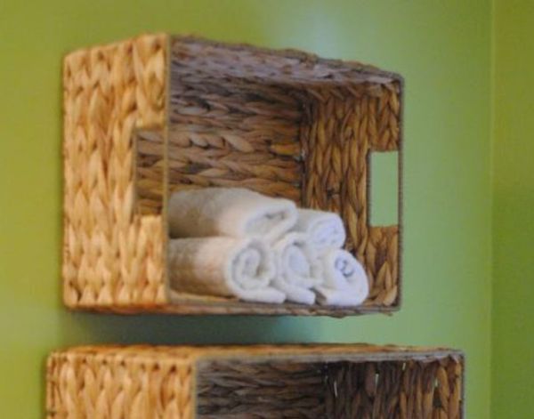 Woven baskets mounted on the wall with towels rolled inside.