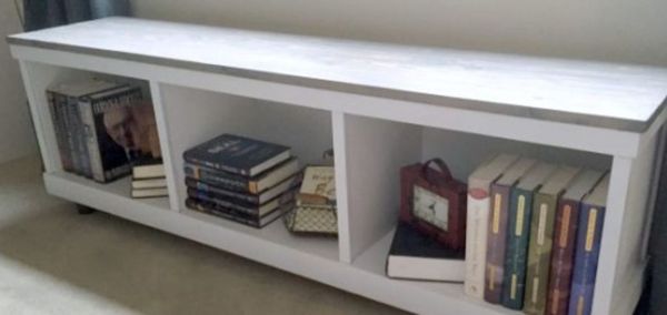 A white wooden shelf holding books.